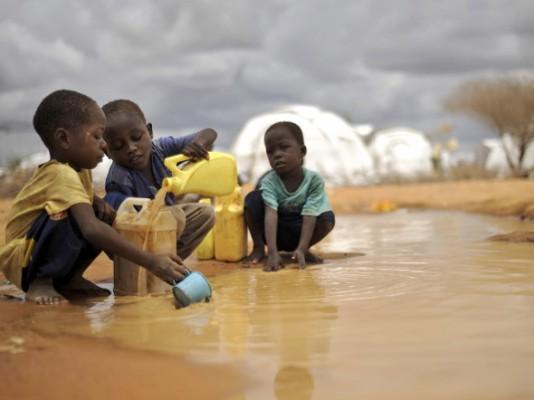 Somaliska pojkar hämtar vatten från en pöl i det vidsträckta flyktinglägret Dadaab i Kenya i oktober 2011. Humanitära organisationer varnar för fruktansvärda förhållanden på världens största flyktingläger. (Foto: Tony Karumba/AFP/Getty Images)