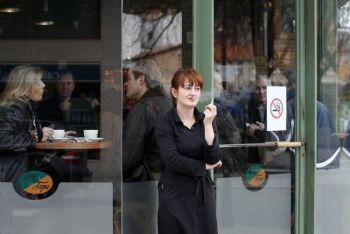 En kvinna röker en cigarett utanför ett café i Burgos, Spanien, efter att förbudet mot rökning på alla barer, restauranger och allmänna platser trädde i kraft den 2 januari. (Foto: Cesar Manso/Getty Images)