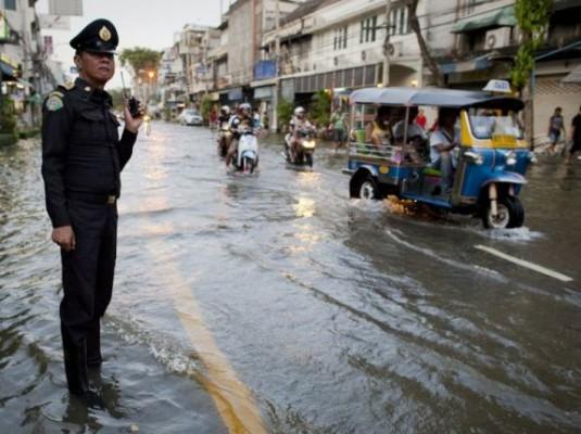 En polis står i flodvattnet på en gata nära Chao Praya-floden i Bangkok den 26 oktober. Boende i Bangkok har blivit varnade för att översvämningarna kan hålla på i fyra veckor. (Foto: Nicolas Asfouri / AFP / Getty Images)