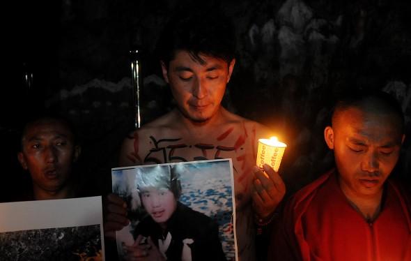 En exiltibetan håller upp en bild av Sangay Gyatso under en ljusvaka som hölls som en sympatiyttring för den 27-årige mannen, som valde att bränna sig till döds. I helgen dog ännu en tibetansk man, i Gansuprovinsen, efter att ha satt eld på sig själv. (Foto: STR/AFP/GettyImages)