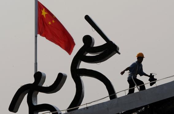 En migrantarbetare slutför byggnadsarbeten intill ett konstverk kopplat till OS. När spelen började tvingades de tusentals migrantarbetare som byggt OS-anläggningarna bort från Peking. (Foto: AFP)