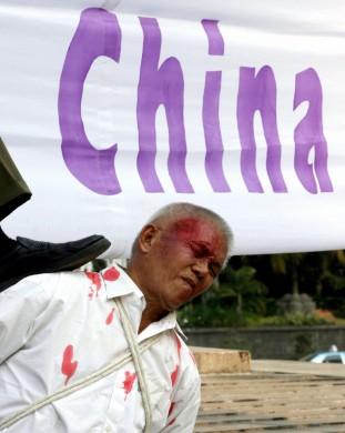 Indonesiska Falun Gong-utövare visar upp hur kinesisk polis torterar fångar under en protest i Jakarta den 7 oktober 2006. Adek Berry/AFP/Getty Images)