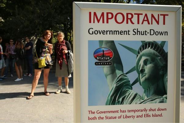 Folk läser på skylten som informerar att Frihetsgudinnan är stängd den 1 oktober i New York. Rederala museer och parker i hela landet är stängda för första gången på nästan två decenier. (Foto: Spencer Platt/Getty Images)