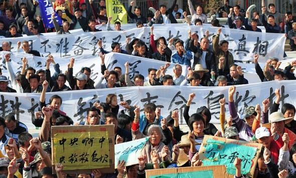 Bybor håller upp banderoller under ett protestmöte i Wukan i Guangdongprovinsen, 19 december 2011. De krävde att de centrala myndigheterna skulle agera mot illegala markövertaganden och att en lokal ledare dött i myndighetsförvar. (Foto: STR/AFP/Getty Images)