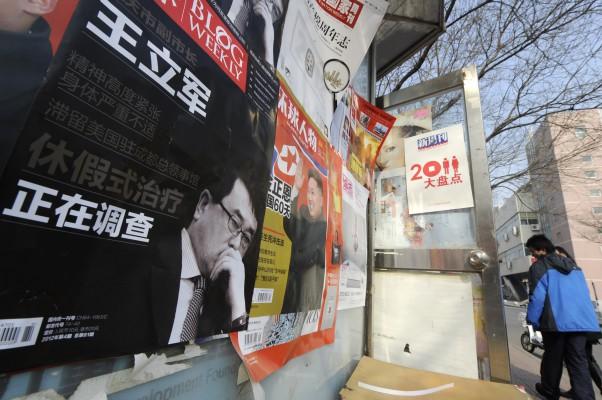 Lokalbefolkningen går förbi en affisch med en bild av en kinesisk tidning som visar den tidigare polischefen i Chongqing, Wang Lijun, på en gata i Peking den 20 februari 2012. (Foto: Liu Jin/AFP)