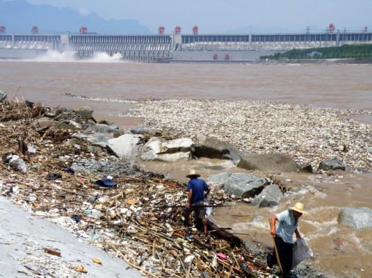 Två arbetare rensar upp sopor längs Yangtzeflodens strand, i närheten av Tre Ravinernas damm i Yichang i Hubeiprovinsen, augusti 2010. (Foto: STR/AFP/Getty Images)