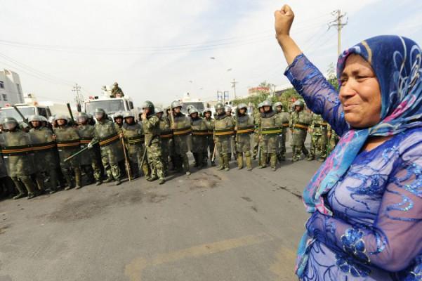 På denna arkivbild betraktar kinesiska kravallpoliser en uigurisk kvinna som protesterar i Urumqi i den västliga regionen Xinjiang i Kina, den 7 juli 2009. (Peter Parks/AFP/Getty Images)
