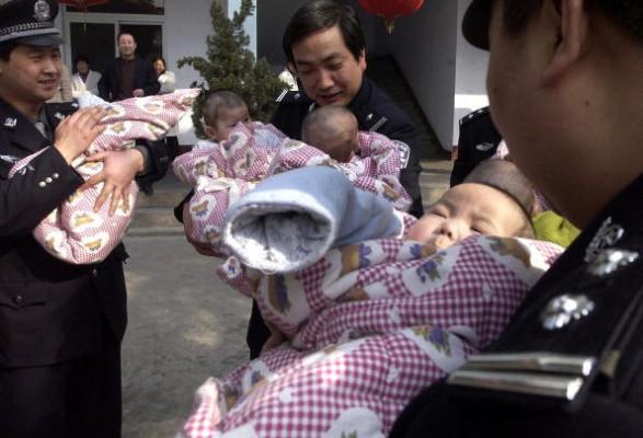 Kinesisk polis tröstar barn som räddats från en grupp människohandlare i Henanprovinsen den 6 maj 2005. Familjerna till tio spädbarn som nyligen räddades från en trafficking-liga gjorde inte anspråk på dem. (Foto: STR/AFP/Getty Images )