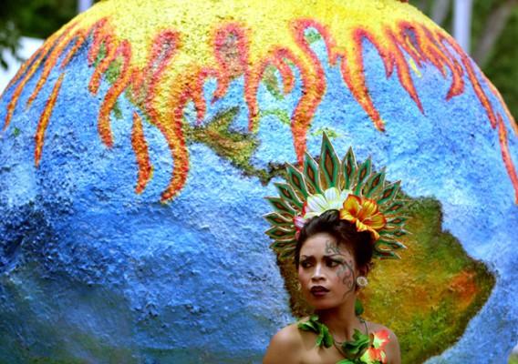 En dansare utklädd till blomma framför en stor jordglob i samband med FN:s klimatkonferens på Bali. Flera NGO:s protesterade mot utökad produktion av agrobränsle. (Foto: AFP)