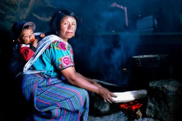 En kvinna i Guatemala lagar mat över öppna elden med barnet lindat på sin rygg. (Foto: Med tillstånd av Nigel Bruce)