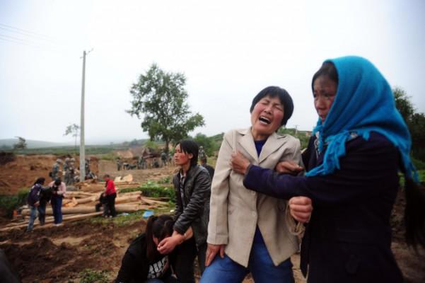 Sörjande människor i bydistriktet Yongguan i Mingxi-häradet som väntar på att omkomna från jordbävningen i Gansuprovinsen den 23 juli ska begravas. På tisdagen sade myndigheterna att dödssiffran har stigit till 95. (Foto: STR/AFP/Getty Images)