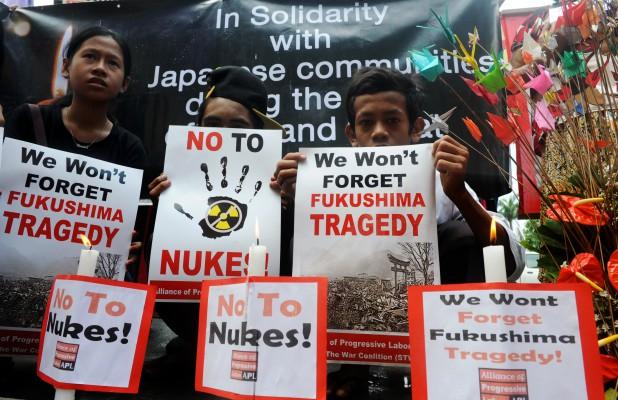 Filippinska miljöaktivister mot kärnkraftverk håller i plakat under en minnesstund för tsunami- och jordbävningsoffren i Japan 2011, framför den japanska ambassaden i Manila den 12 mars. Aktivisterna sade att katastrofen på kärnkraftverket i Fukushima förstörde hela illusionen av hur säker kärnkraften är i hela världen. (Foto: Jay Directo/AFP)
