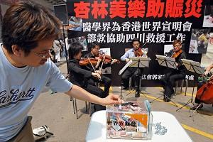 En man som lägger pengar i en insamlingsbössa under en kampanj som hålls av en grupp musiker i Hongkong för att samla in pengar till jordbävningens offer . (Foto: AFP)