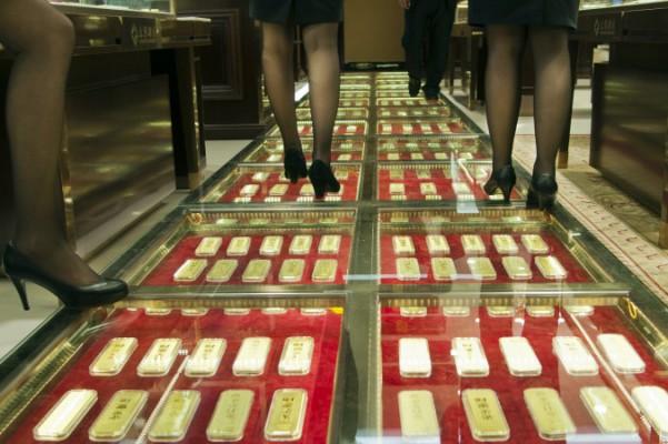 Kinesiska säljare promenerar längs en gång med guldtackor i golvet på ett guldväxlingskontor i Kunming, Kina, 11 december 2012. Foto: STR/AFP/Getty Images