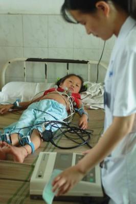 En sköterska kontrollerar kardiogram på en liten flicka som blev sjuk av vaccin på ett sjukhus i Kina. (China Photos/Getty Images)