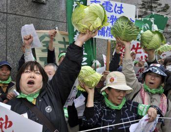 Jordbrukare håller upp kålhuvuden under en protestaktion utanför TEPCO:s huvudkontor i Tokyo den 26 april. Uppemot 350 demonstranter samlades för att hålla tal och kräva kompensation för sina ekonomiska förluster orsakade av kärnkraftsolyckan. (Foto: Yoshikazu Tsuno/Getty Images )