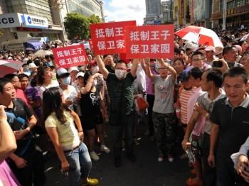 Demonstranter ropar slagord och håller upp banderoller utanför lokalregeringens byggnad i Qidong i Kina. Protesterna kan växa ytterligare de kommande dagarna om fler personer deltar såsom de lovat på nätet.  (Foto: Peter Parks/AFP/Getty Images)

