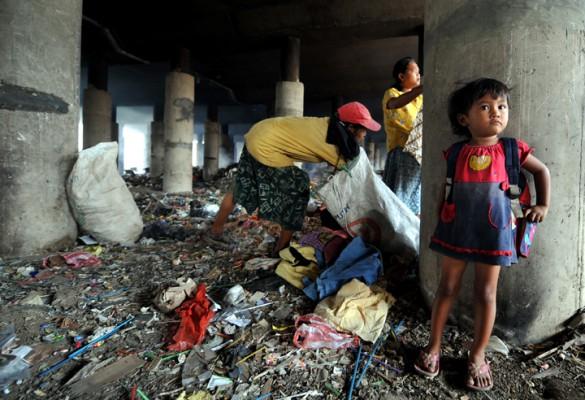 En mamma med dotter letar efter mat under en motorvägsbro i Jakarta. Malaysia har drabbats av kraftig inflation som slår mot de allra fattigaste. (Foto: AFP)