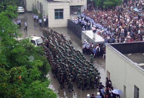 Poliser i formation vid grinden till lokalregeringens byggnad i Lichuan, Hubei-provinsen den 9 juni. 1500 personer demonstrerade sitt missnöje över en person som dött i polishäktet