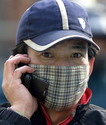 Intensivt och långvarigt mobiltpratande kan öka risken för hjärntumör. Det är dock inte det utan Shanghais bitade vindar som denna kinesiske telefonör skyddar sig. (Foto: LIU JIN/AFP)
