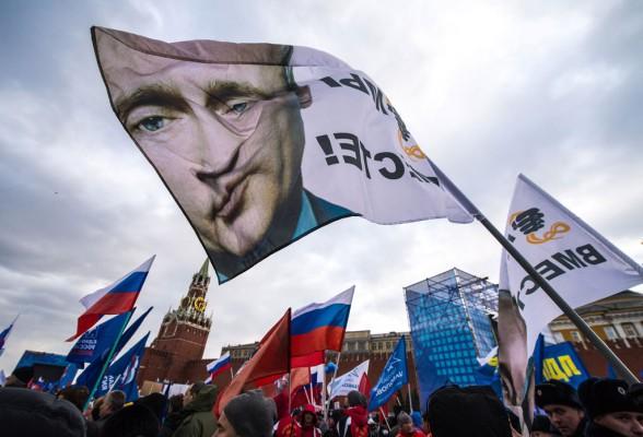 Pro-ryska aktivister samlades med Vladimir Putins bild på en flagga, på Röda torget i Moskva den 18 mars 2014, för att fira övertagandet av Krim. Putin har på alla sätt försökt rättfärdiga införlivandet av Krim. (Foto: Dmitry Serebryakov / AFP / Getty Images)