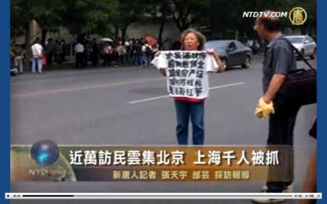 <p>En petitionär håller upp en T-shirt med slagord på bröstet. Tusentals petitionärer rapporteras ha samlats i Peking på fredagen den 31 maj inför årsdagen av massakern den 4 juni 1989. Myndigheterna packade in dem i bussar. (Skärmdump från NTD Television via Epoch Times)
