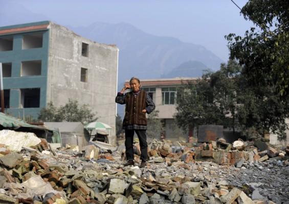 Denna kvinna i samhället Leigu, Beichuanlänet i Kinas Sicuanprovins, överlevde den kraftiga jordbävningen. Men hennes hus, på vars rester hon står och ringer i mobiltelefonen, gjorde det inte. Återuppbyggnaden av de raserade städerna har dragit ut på tiden och den kinesiska statens bristande hjälp till de drabbade har kritiserats. (Foto: AFP)
