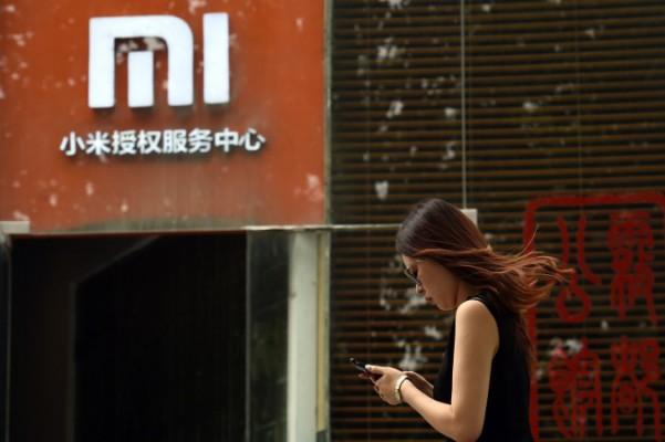 En kvinna kollar telefonen utanför kinesiska telefontillverkaren Xiaomis servicecenter i Peking. Xiaomi är en av flera tillverkare vars telefoner har visat sig vara förinstallerade med skadlig mjukvara redan när de kommer i konsumentens händer. Foto: Greg Baker /AFP/ Getty Images