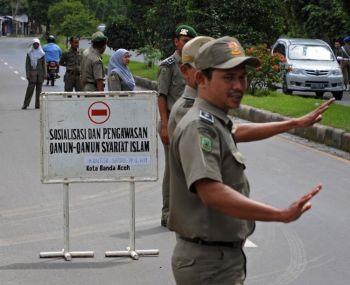 Indonesiens islamiska sharia-polis vid en vägspärr i Aceh vinkar till sig kvinnliga trafikanter som bär åtsittande byxor och kjolar. Hittills har överträdelserna resulterat i tillfälliga anhållanden men kvinnorna kan nu frihetsberövas i veckor. (Foto: Romeo Gacad / Getty Images)