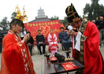 Förenade av ödet: Ett nygift par, klädda i traditionella Handräkter, dricker vin från ett par koppar som förenats med en röd tråd, i staden Xian, Kina. Legenden om den röda tråden har lett till en mångfald traditioner. (Foto: China Photos / Getty Images)
