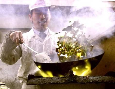 Att laga mat med en wok går snabbt när man väl lärt sig tekniken. Utomhuskök med snabbwokad mat är en vanlig syn i hela Kina. (Foto: Stephen Shaver/AFP)