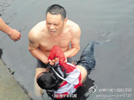 Zhang drar upp en fjortonårig ​​flicka från det stinkande flodvatten där hon försökte begå självmord.  Dagen efter att han hade hoppat ner i den kraftigt förorenade floden för att rädda tonåring, lades Zhang in på sjukhus med kräkningar och yrsel. (Foto: Weibo.com)