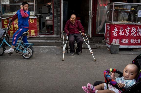 En gammal man sitter utanför sitt hus i Peking. (Foto: Kevin Frayer/Getty Images)