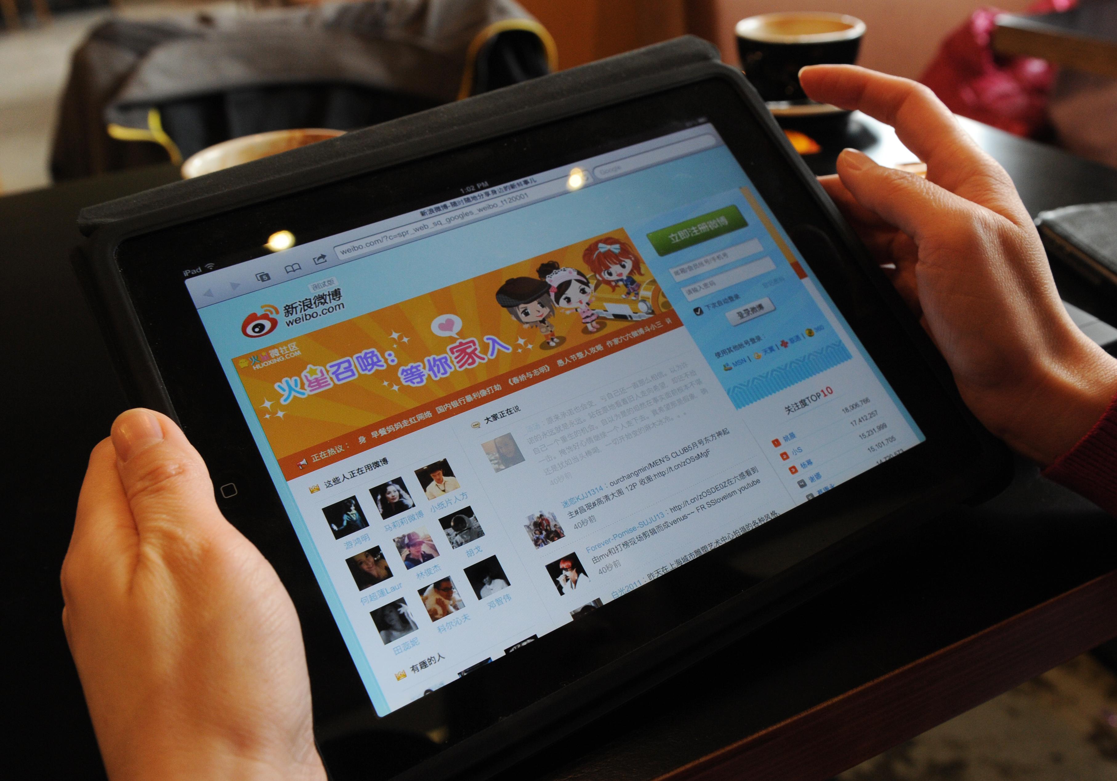 En kvinna tittar på mikrobloggen Weibo på en läsplatta. Att i Kina sprida information på internet som regimen anser vara "rykten" kan från och med den 1 november ge långa fängelsestraff.  (MARK RALSTON/AFP/Getty Images)