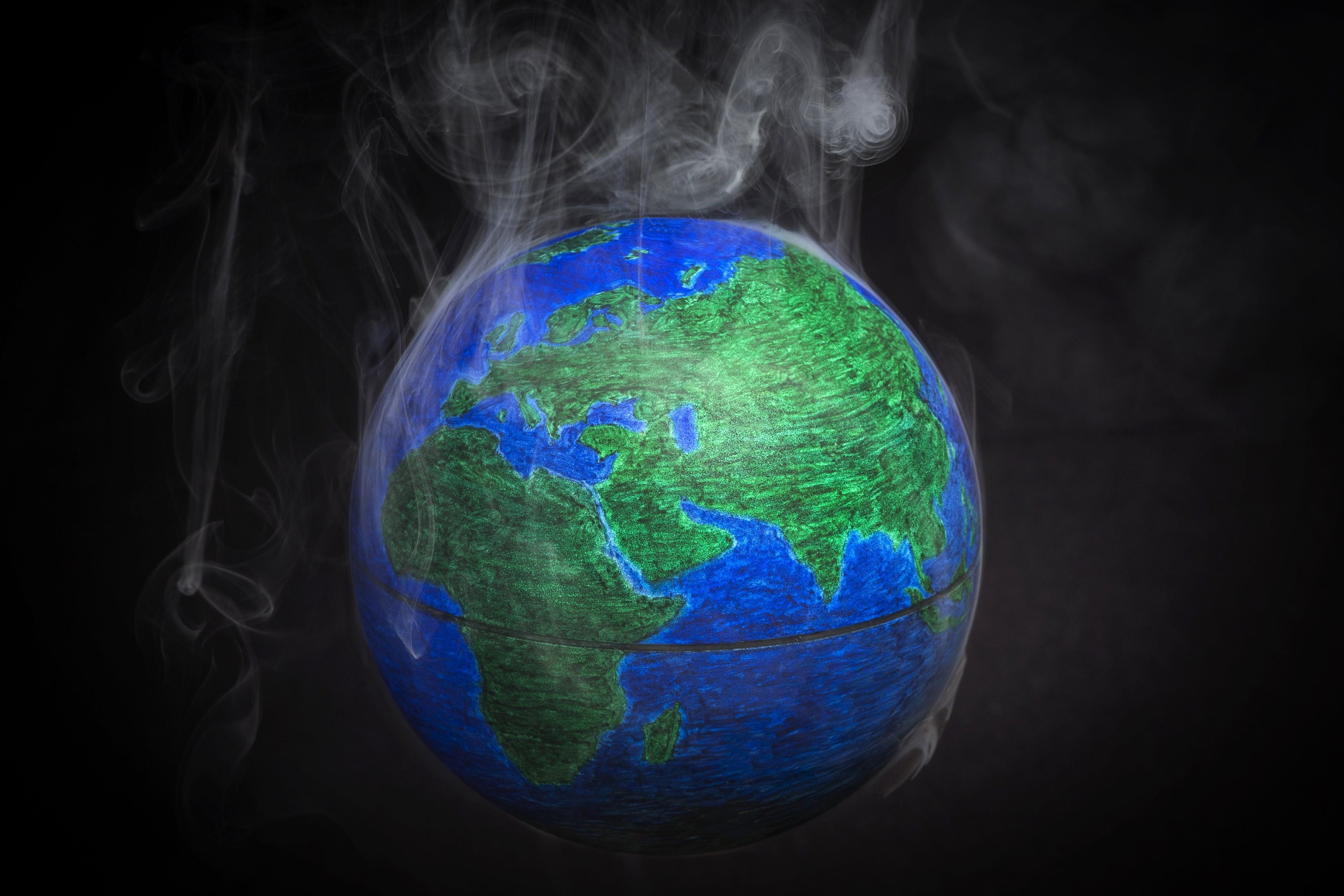Jordgloben med rök omkring symboliserar den globala uppvärmningen. EU-länderna vill begränsa uppvärmningen till två grader Celsius. Nu har höjningen nått över en grad. (Foto: Lionel Bonaventure /AFP/Getty Images) 