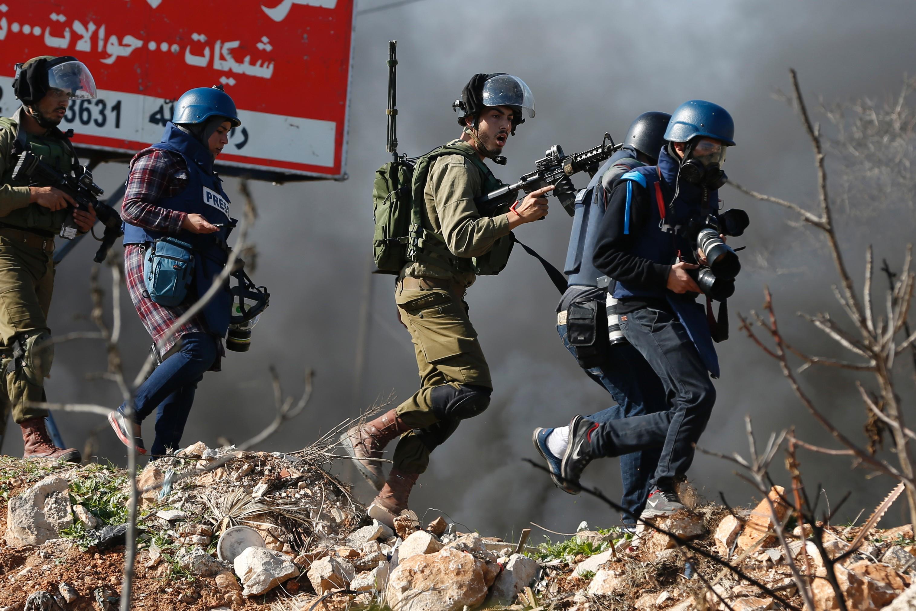 Journalister lever farligt i krigsområden. Här motar en israelisk soldat bort journalister under en sammanstötning med palestinska ungdomar på Västbanken. (Foto: Abbas momani/AFP/Getty Images)