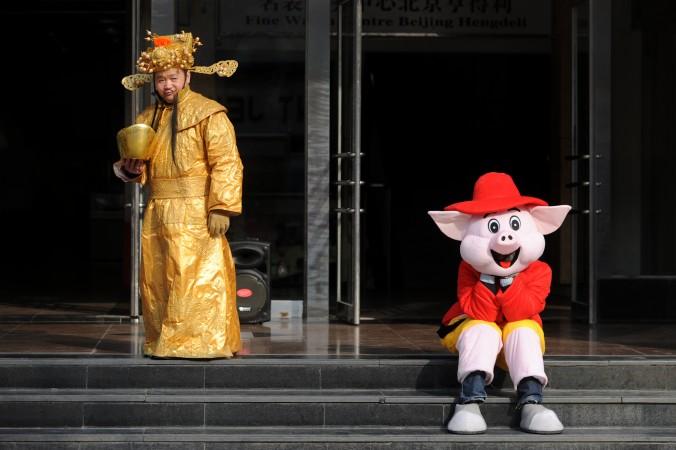 På ett shopping center i Peking väntar två säljare, uppklädda till rikedomens gud och en seriefigur, på sina kunder. (Foto: Wang Zhao/AFP/Getty Images)