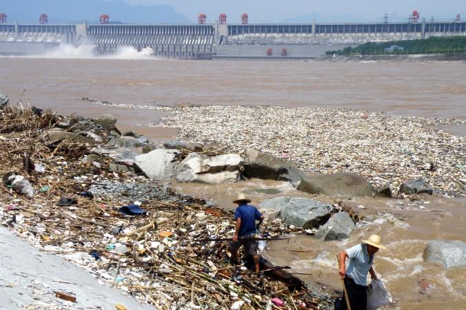 Arbetare städar längs Yangtzefloden, vid De tre ravinernas damm i Yichang, i Hubeiprovinsen i Kina. Kinas ledare Xi Jinping har i ett tal lovat att stoppa exploateringen av floden för att rädda den. (Foto: STR/AFP/Getty Images)