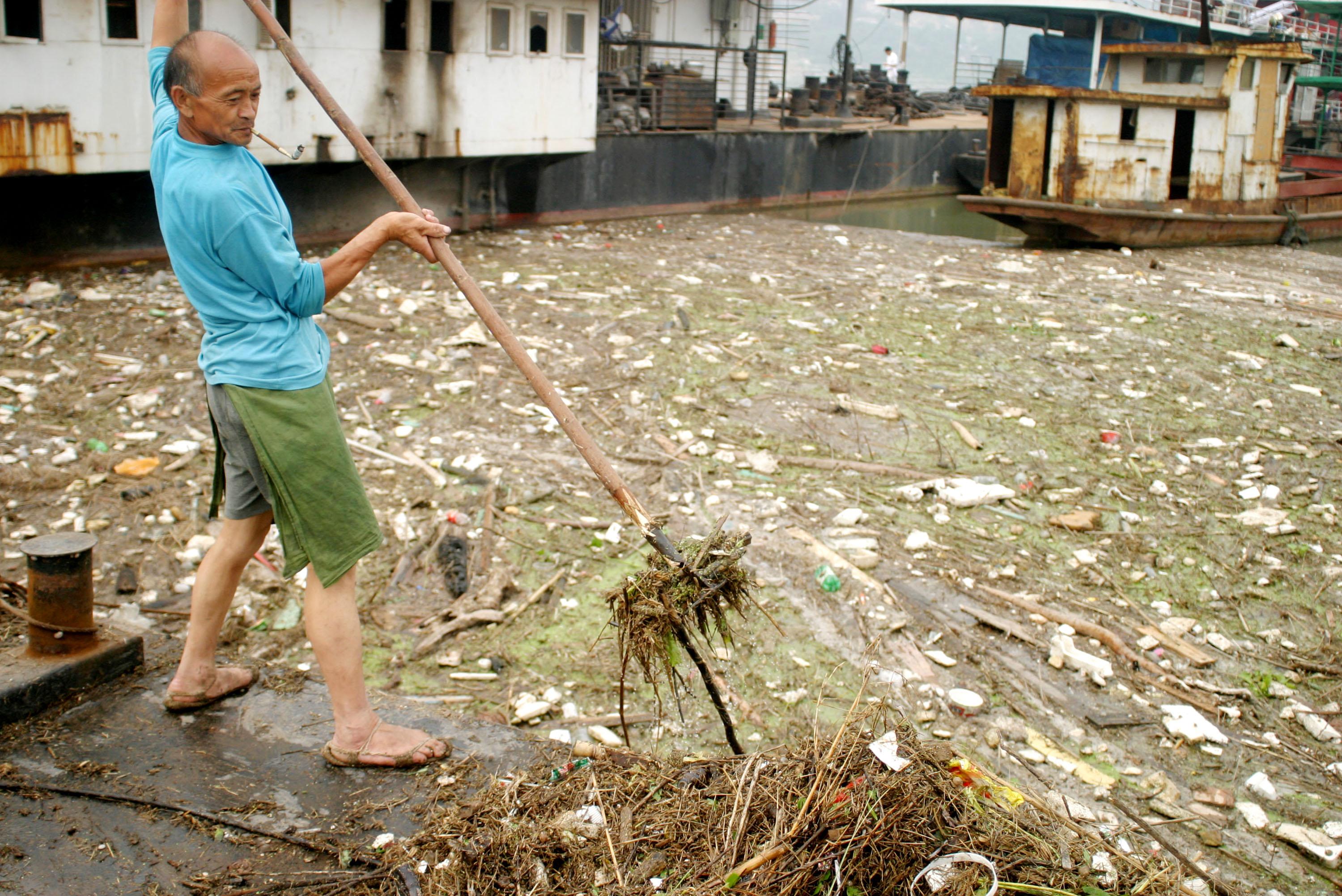 En man rensar bort skräp från Yangtzefloden i Wushan, Kina, 2003. Nyligen fastställdes den hittills hårdaste domen för vattenföroreningar i Kina, men uppförsbacken är brant i det kinesiska miljöarbetet. Till exempel bedöms vattnet i 36 procent av floderna som "mycket dåligt". (Foto: Getty Images)