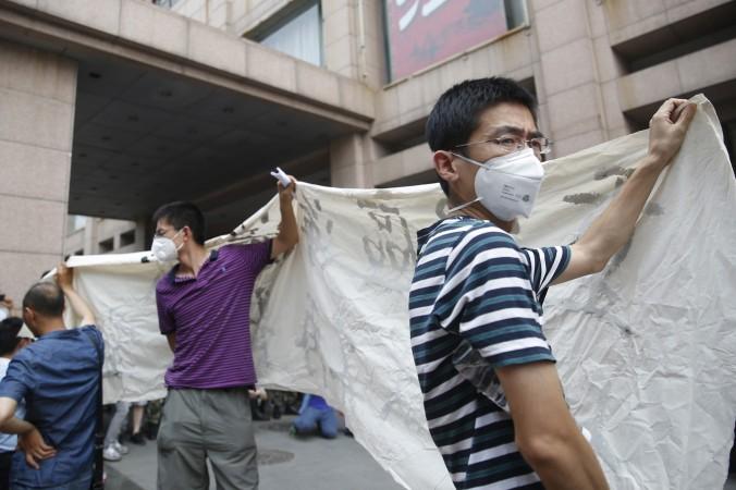 Lägenhetsinnehavare som fick sina hem förstörda när en lagerbyggnad med kemikalier exploderade i hamnen i Tianjin protesterar, den 17 augusti 2015. (Foto: STR/AFP/Getty Image)