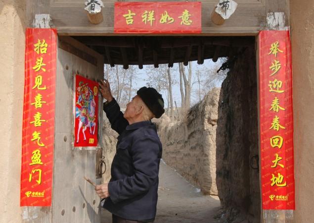 Inför nyårsfirandet sätter en äldre man upp nyårsverser (Chun Lian) vid sin dörr i Shaanxiprovinsen. Det centrala propagandadepartementet utfärdade i slutet av december 2015 riktlinjer för vad medborgarna får skriva på sina nyårsdekorationer. (Foto: China Photos/Getty Image)