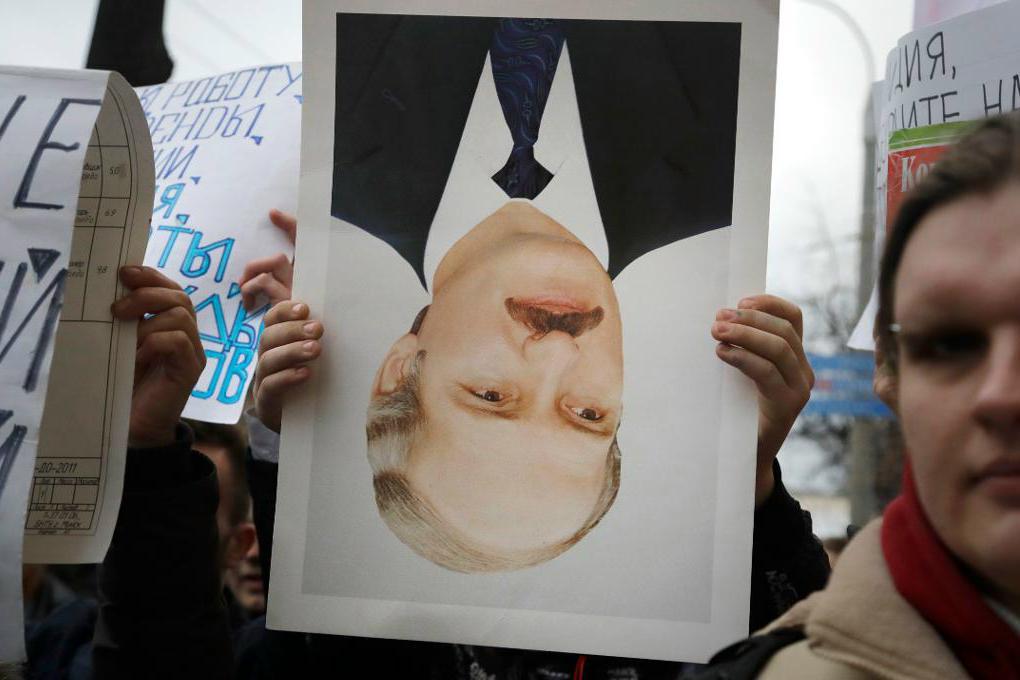 
En demonstrant håller i uppochnervänd bild på den vitryske presidenten Aleksandr Lukasjenko under en protest i Minsk. Foto: Sergej Grits/AP/TT                                            