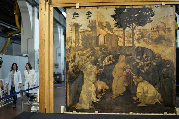 Två konstrestaurerare går förbi da Vincis målning "Konungarnas tillbedjan" på Opificio delle Pietre Dure 2014 när konstverket fortfarande restaurerades. Nu är målningen tillbaka på Uffizi Gallry där den ställs ut. Foto: Andreas Solaro/AFP/Getty Images