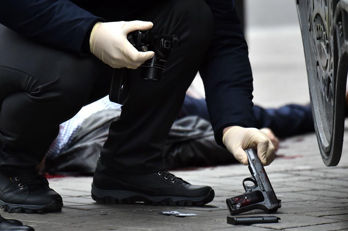 En ukrainsk polis plockar upp ett vapen på platsen där den tidigare ryske parlamentsledamot sköts till döds i Kiev. Foto: Sergei Supinsky /AFP/Getty Images