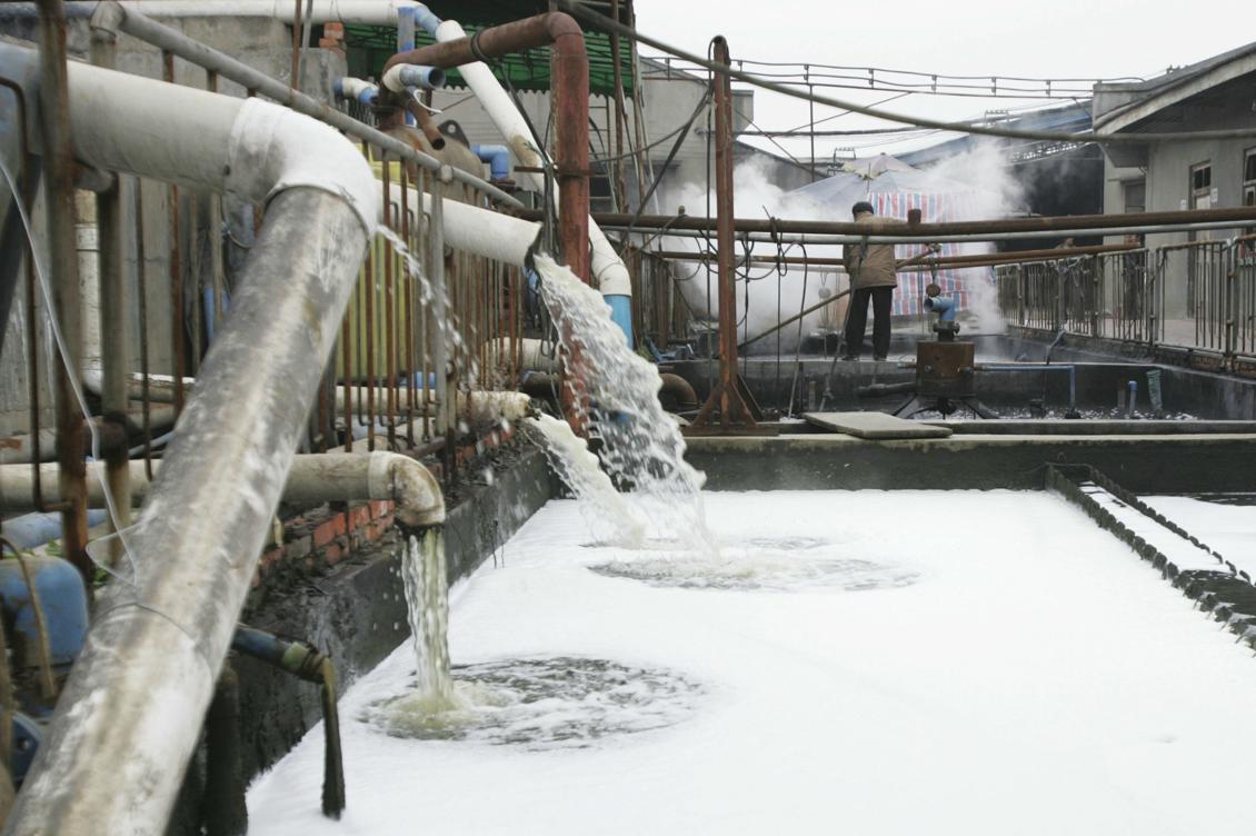 Från rören kommer smutsvatten från en klädfabrik till en bassäng för behandling, i Chengdu, Kina, 2005. Vattenföroreningen är ett stort problem i Kina, som textilindustrin bidrar till. Foto: China photos/Getty Images