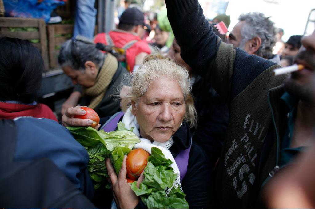
En kvinna tar sig genom folkmassan efter att ha fått gratis grönsaker på torget i Buenos Aires, Argentina. Foto: Victor R. Caivano/AP/TT                                            