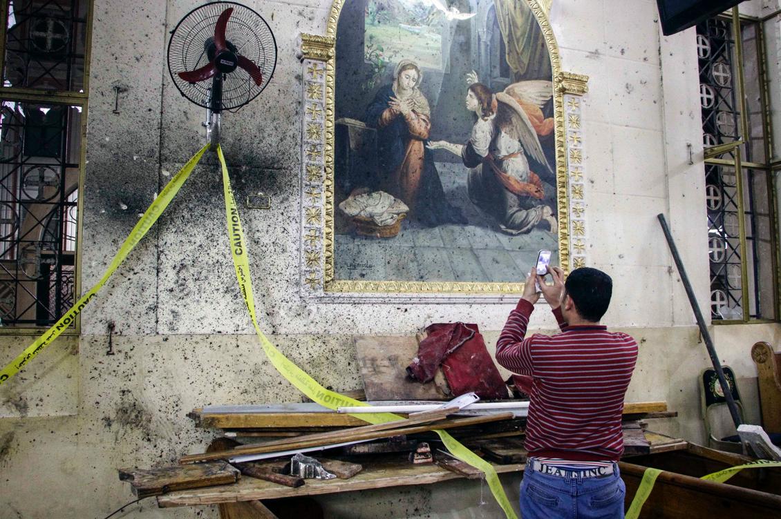 En egyptier tar bilder med sin mobiltelefon i en koptisk kyrka i Tanta efter förödelsen. Foto: Stringer/AFP/Getty Images)
