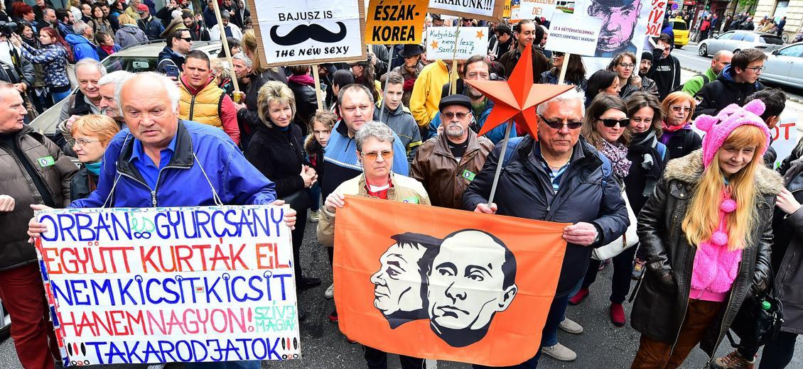 Demonstranterna håller flaggor med porträtt av den ryska presidenten Vladimir Putin och den ungerska premiärministern Viktor Orban i sin ironiska protest. Foto: Attila Kisbenedek/AFP/Getty Images. 