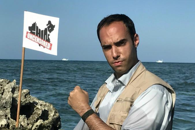 China Uncensoreds programledare Chris Chappell planterar programmets flagga på ett rev på det omstridda Scarborough Shoal i Sydkinesiska havet. I bakgrunden syns två kinesiska kustbevakningsfartyg. Foto: Matt Gnaizda/China Uncensored