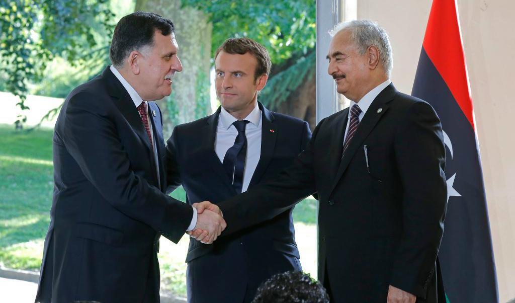 Libyens premiärminister Fayaz al-Sarraj till vänster och general Khalifa Haftar till höger skakar hand. Efter samtal ledda av Frankrikes president Emmanuel Macron (i mitten) har rivalerna kommit överens om ett vapenstillestånd. Foto: Michel Euler/AP/TT